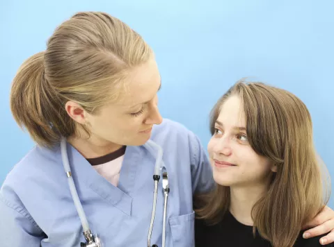 A female medical professional comforts a young girl.