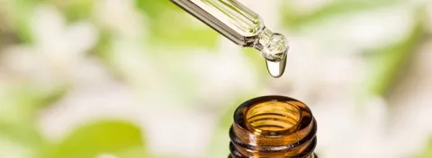CBD oil drips from a pipette into a medicinal bottle.