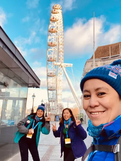 Women in winter hats in front of London Eye