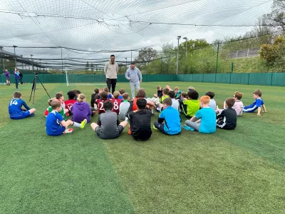 Children gathered around on the pitch to hear Jay speak