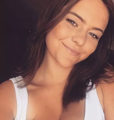 Jasmine, a young woman in white vest, smiles with her head tilted in a selfie.