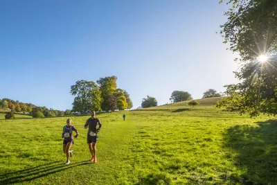 A woman and man running down a grassy hill