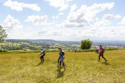 A group of people walking across a field with panoramic views behind
