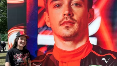 Young girl poses next to poster of racer driver