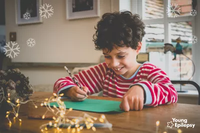 young boy writing a chrostmas list