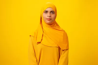 Zunera wearing a yellow head scarf in front of a yellow backdrop