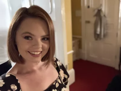 A young woman with a bob smiles widely into the camera.