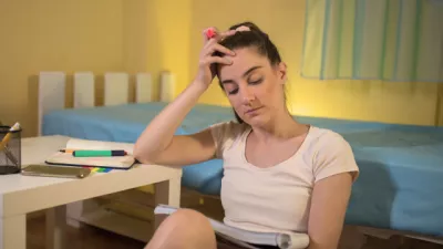 Young girl sitting on the floor, revising for exams with head in hands