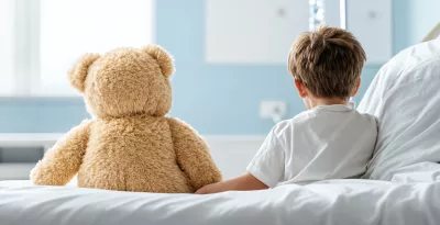 Child and teddy sitting on hospital bed facing away