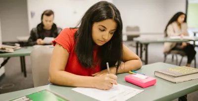Young girl writing on an exam paper in an exam hall