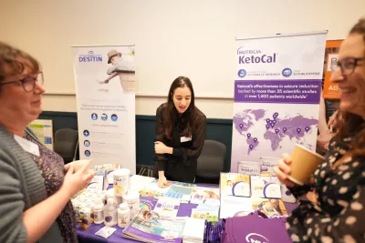 A woman shares information pamphlets and leafets at a table at a Young Epilepsy research retreat.