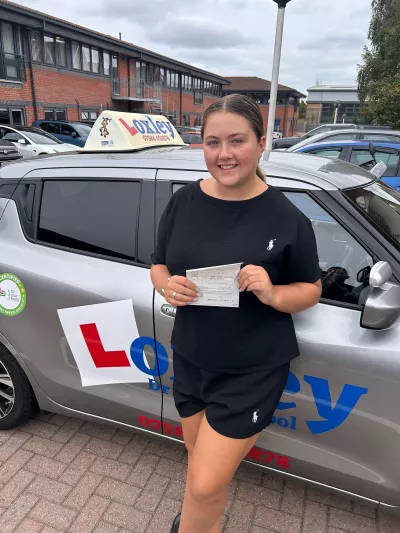 A young woman stands by a learner car, showing that she passed her driver's license.