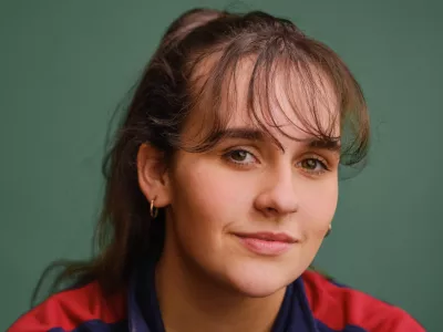 A young woman with a fringe, Rebecca, poses and smiles.