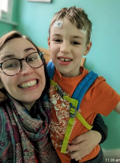 A mother and son smile while the son wears an EEG.