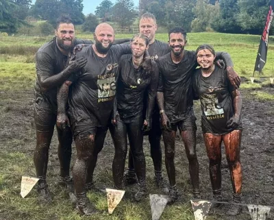 Muddy group of friends smiling at a cemera