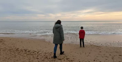 A mother approaches her son on a sunset beach.