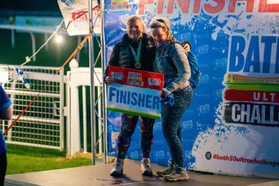 2 event participants  posing with a finisher sign