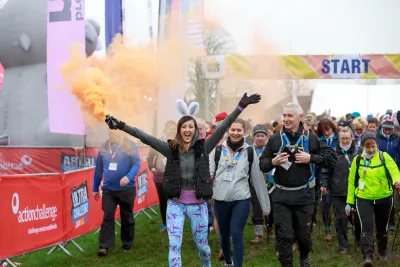 Walkers through a start archway with coloured smoke 