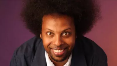 Prince Abdi smiles to camera against a dark red background.
