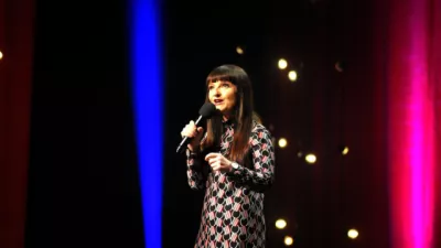 Jo Enright hold a microphone on a stand-up stage.