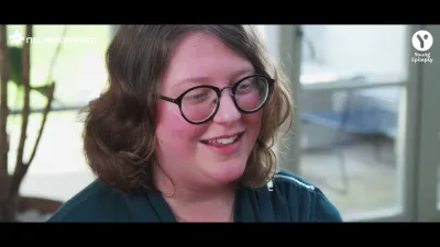 A young woman in glasses smiles in an interview.