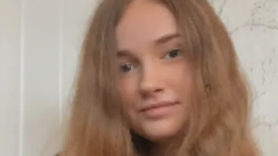 Paige smiles slightly to camera.