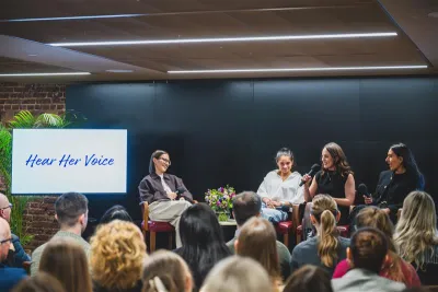 A crowd watches the women on a panel of a Hear Her Voice event.