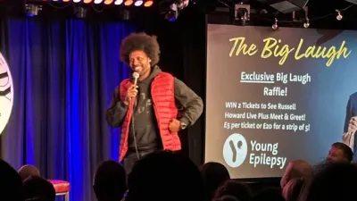A comedian holds the mic on stage at the Big Laugh at the Comedy Store London.