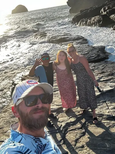 A family smiles for a photo on a beach.