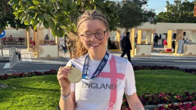 A woman in an England t-shirt holds up a medal.