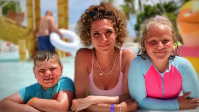 A family rests on the edge of a tropical outdoor pool.
