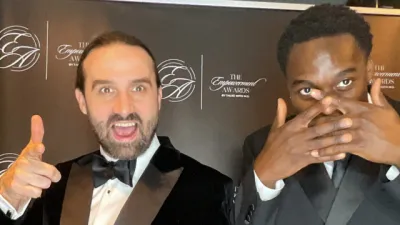 Two young men in suits stand at the step-and-repeat at the Empowerment Awards.