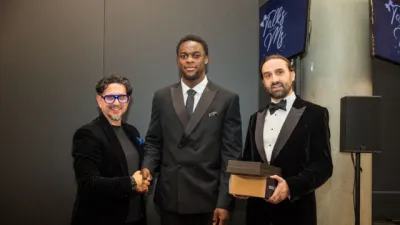 Two young men accept the Charity of the Year award from a third man at the Empowerment Awards.