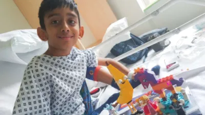 A boy plays with Lego in a hospital bed.