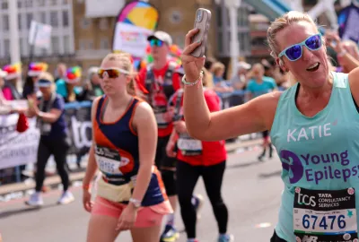 London Marathon Runner holds her phone and waves to the crowds