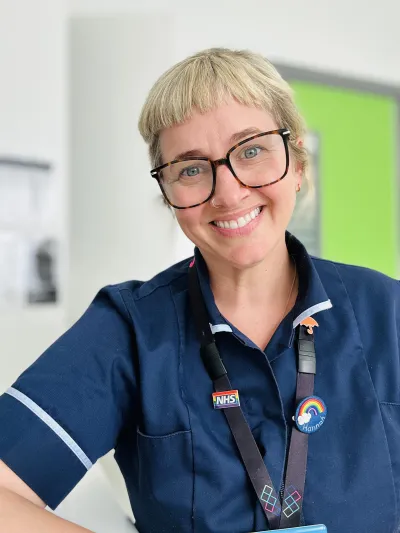 An NHS professional smiles to camera.