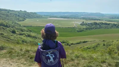 A boy stands on a hill overlooking a beautiful view.