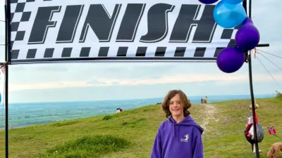 A boy stands on a cliff beneath a 'Finish' race banner.