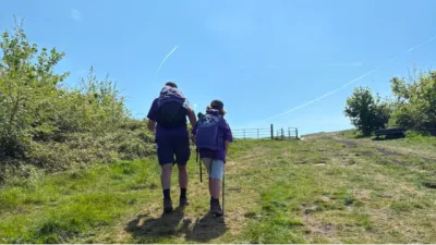 A father and sun hike up a hill.