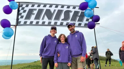 A boy and his parents stand under a 'Finish' line.