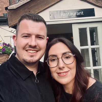 A young couple stand outside a restaurant.
