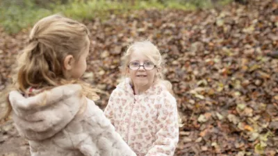 Two little girls play in a forest.