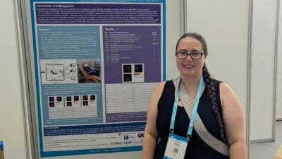 A researcher stands next to a poster of her work.