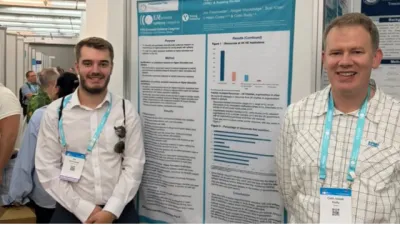 Two men stand beside a poster of their research.