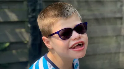 A young boy smiles in sunglasses.