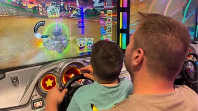 A boy and his dad play a Mario Kart arcade.