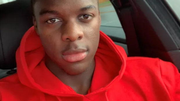 Selfie of a you man in a red hoodie sat in a car.