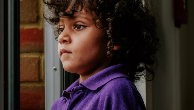 Young boy looks out of window thoughtfuly 