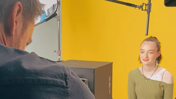 A young woman, Bea, sits before a yellow screen as a cameraman films her for a Young Epilepsy campaign.
