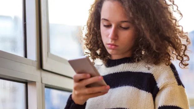 A young person looking at down at her phone concentrating.